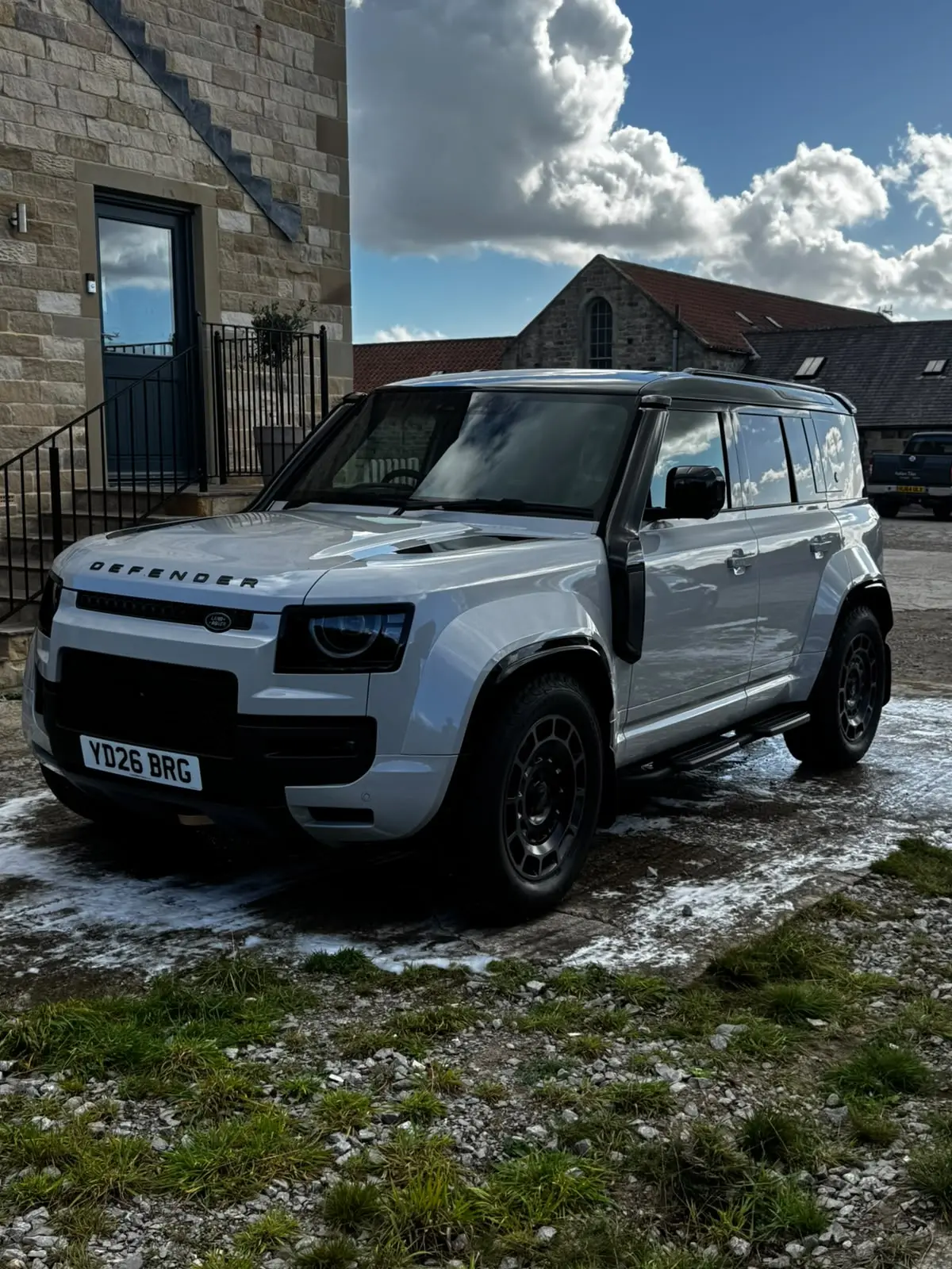 Silver Land Rover Defender 110 with black wheels after a monthly maintenance wash in Harrogate