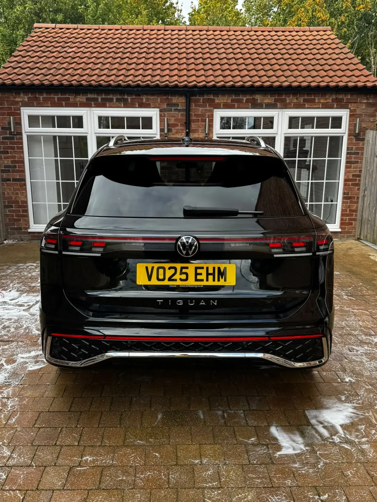 Rear of a black Volkswagen Tiguan R-Line, clean and glossy on a block-paved drive
