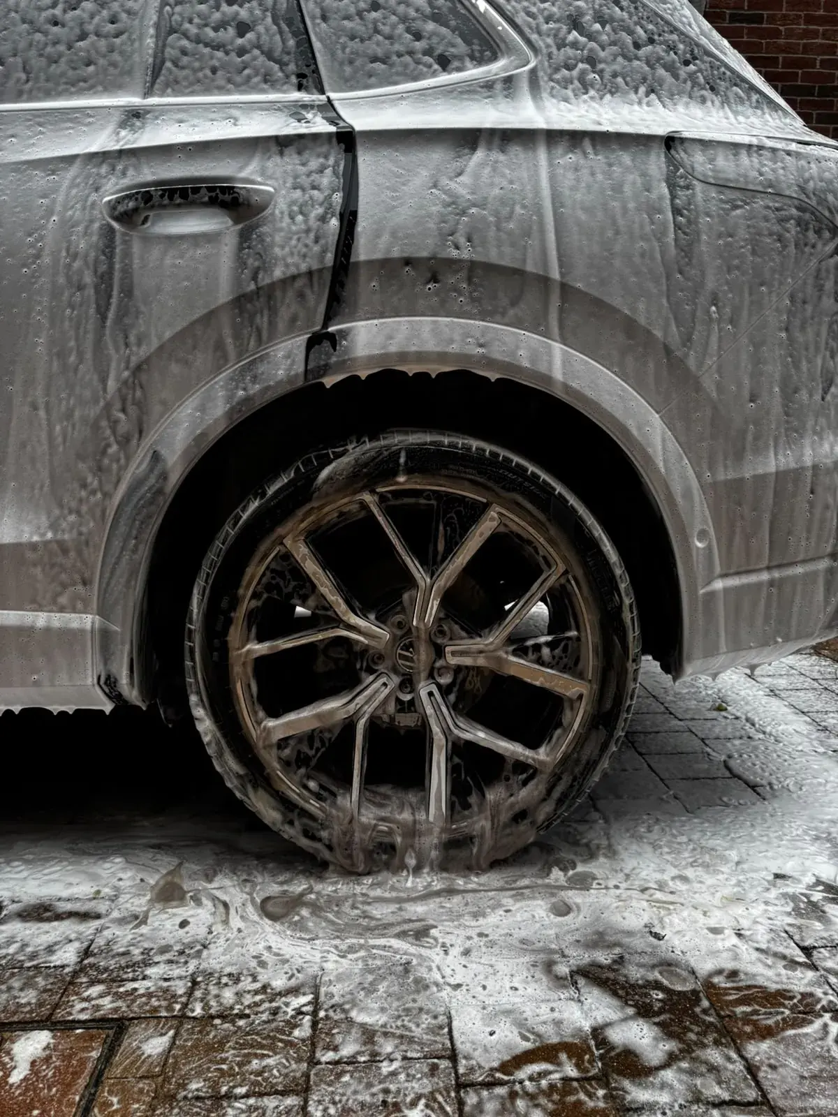 Snow foam running down the rear quarter and wheel of a Volkswagen Tiguan